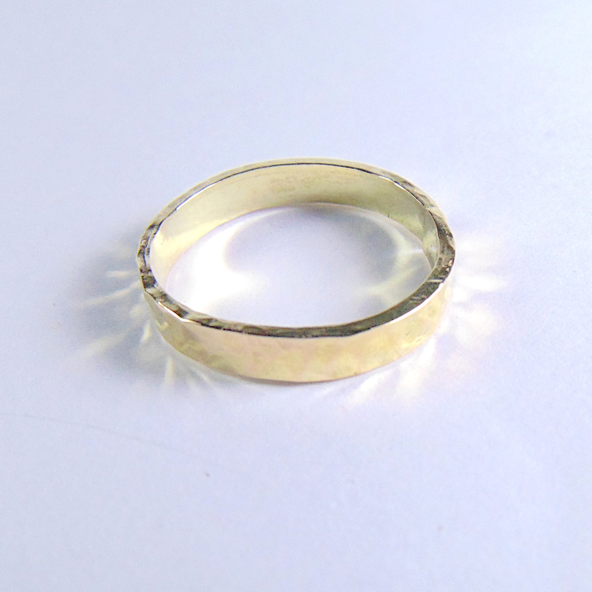 Ręcznie wykonana złota obrączka ślubna z charakterystycznym młotkowanym wykończeniem, nadającym jej unikalny, artystyczny wygląd.