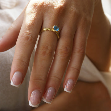 Złoty pierścionek z topazem swiss-blue na ręku
