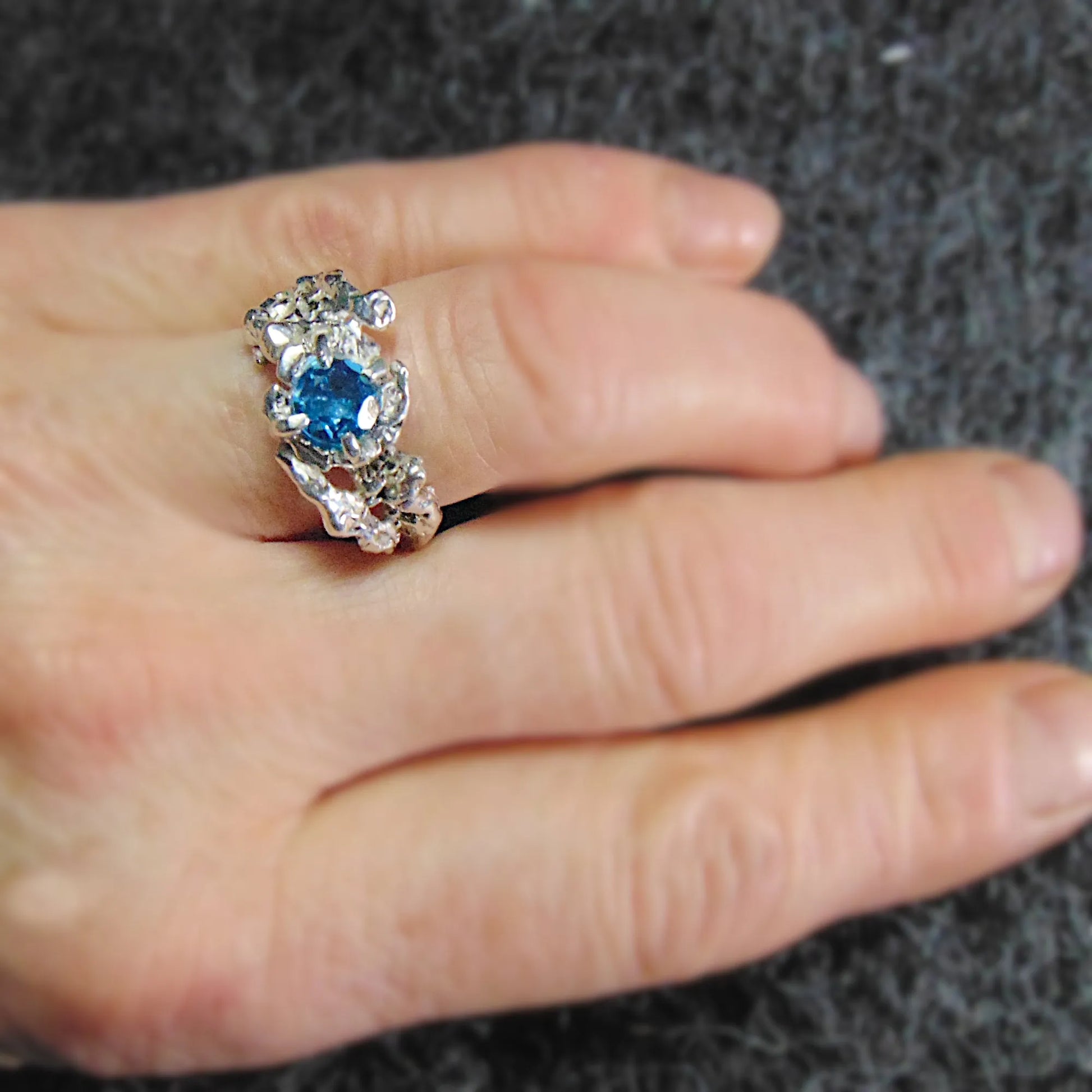 Biżuteria srebrna z topazem Swiss Blue, wyjątkowy design i ręcznie fakturowana powierzchnia- widok na dłoni
